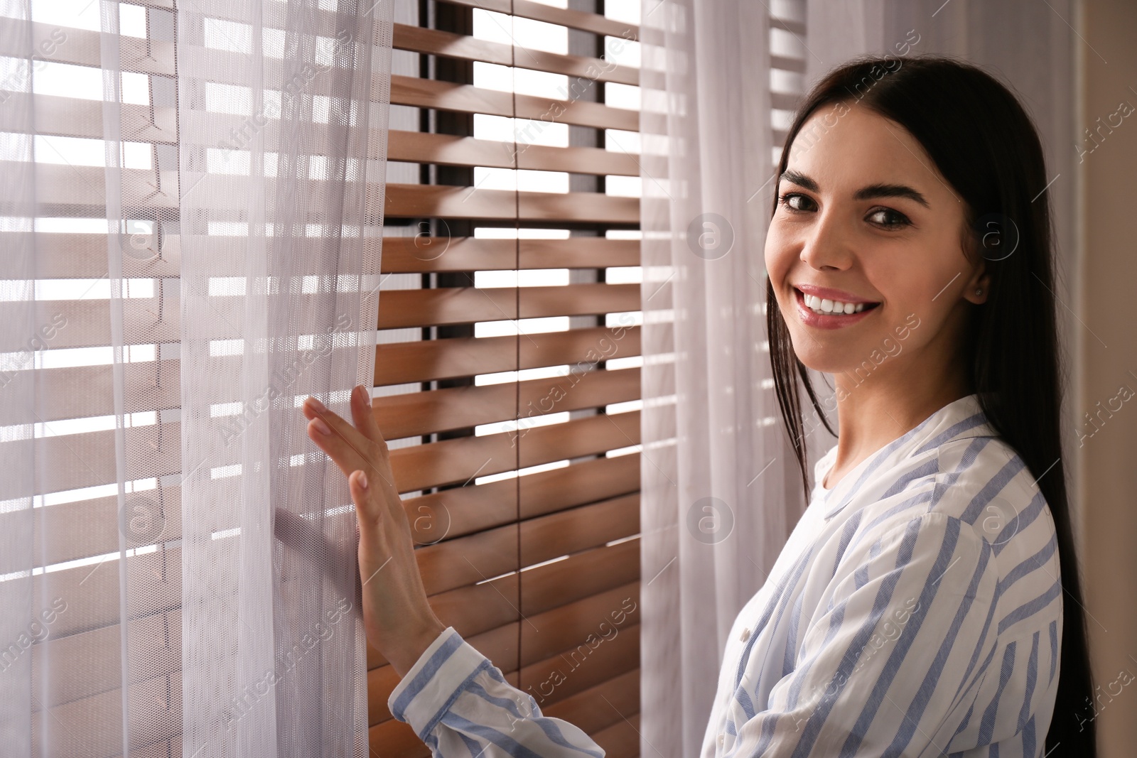 Photo of Woman near window with beautiful curtains at home