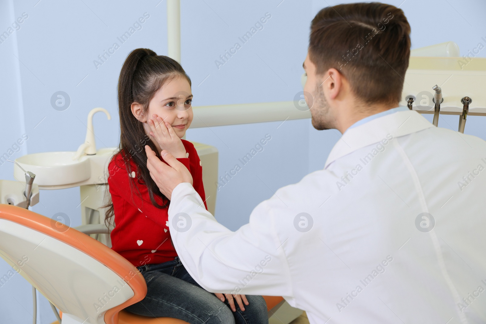 Photo of Professional dentist working with little patient in modern clinic