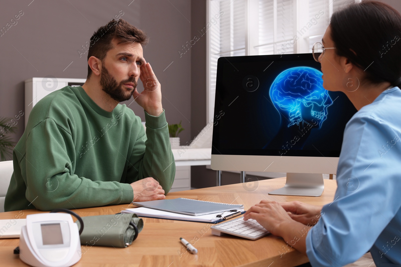 Photo of Neurologist consulting patient at table in clinic