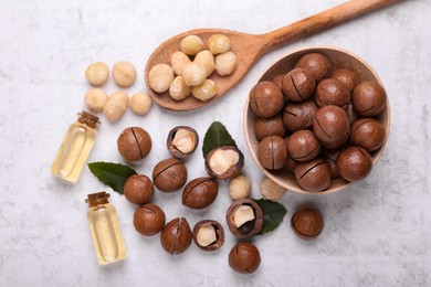 Photo of Delicious organic Macadamia nuts and cosmetic oil on light gray table, flat lay