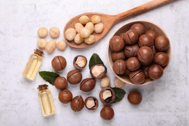 Delicious organic Macadamia nuts and cosmetic oil on light gray table, flat lay