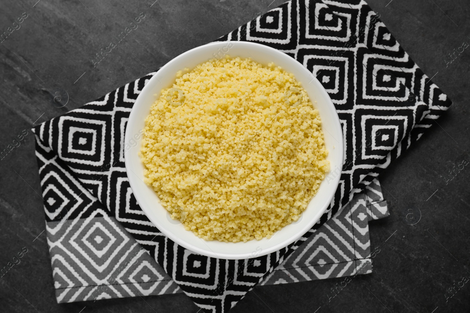 Photo of Bowl of tasty couscous on grey table, top view