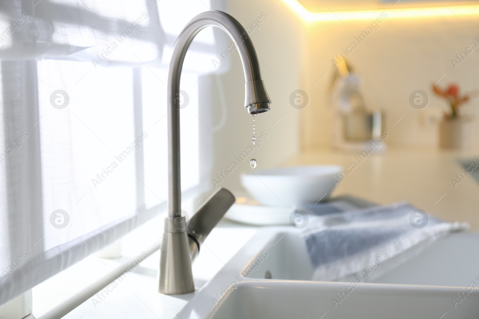 Photo of Water drops falling down from tap in kitchen