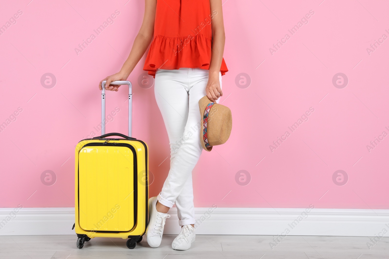 Photo of Woman with suitcase near color wall. Space for text