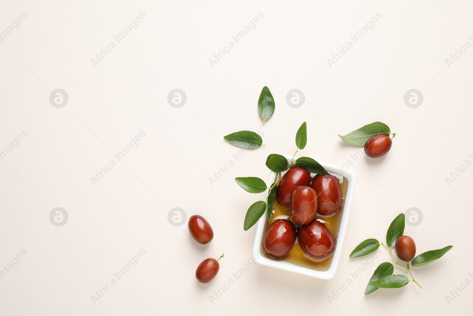 Photo of Sauce boat with jojoba oil and seeds on light background, flat lay. Space for text