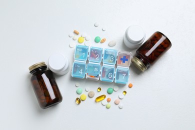 Photo of Weekly pill box with medicaments on white table, flat lay