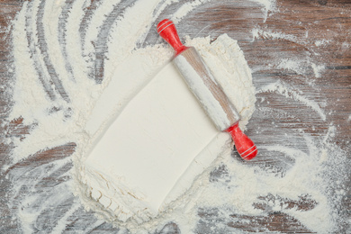 Flour and rolling pin on wooden table, top view. Space for text