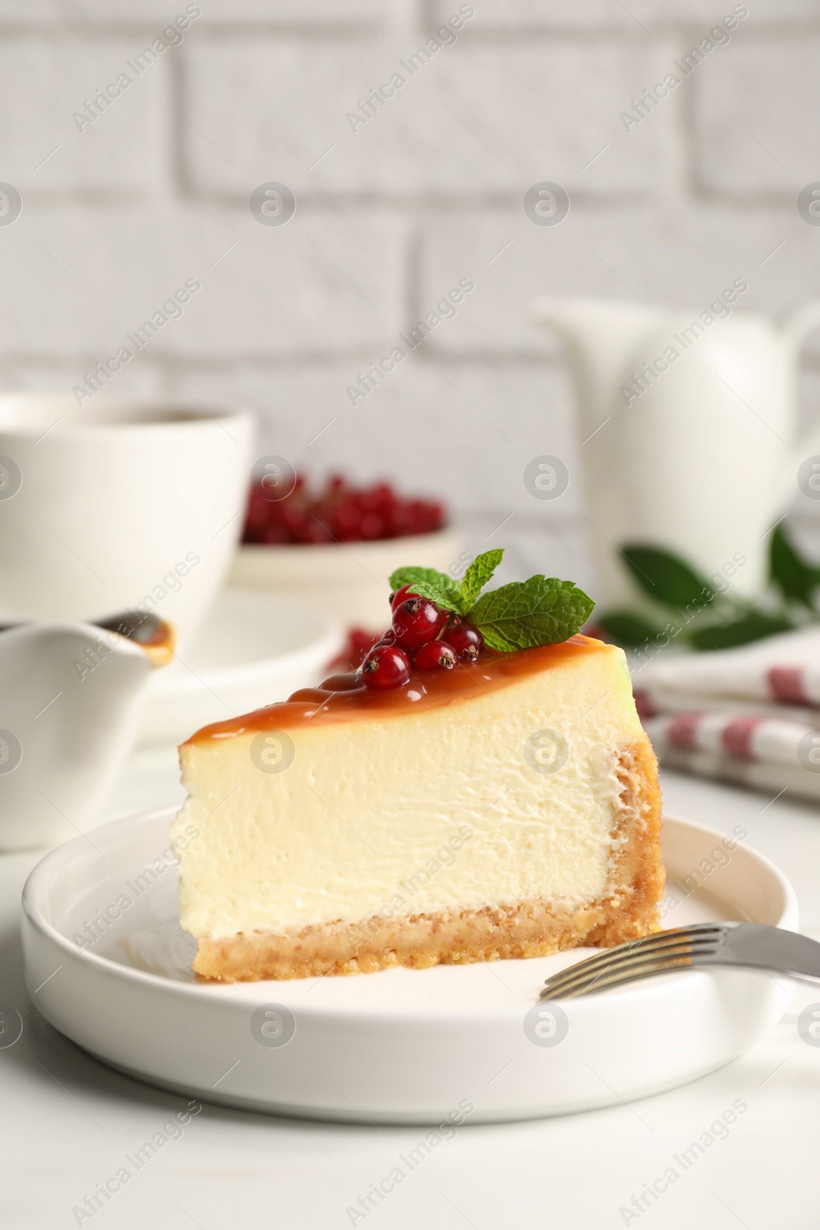 Photo of Piece of delicious caramel cheesecake with red currants and mint served on white marble table