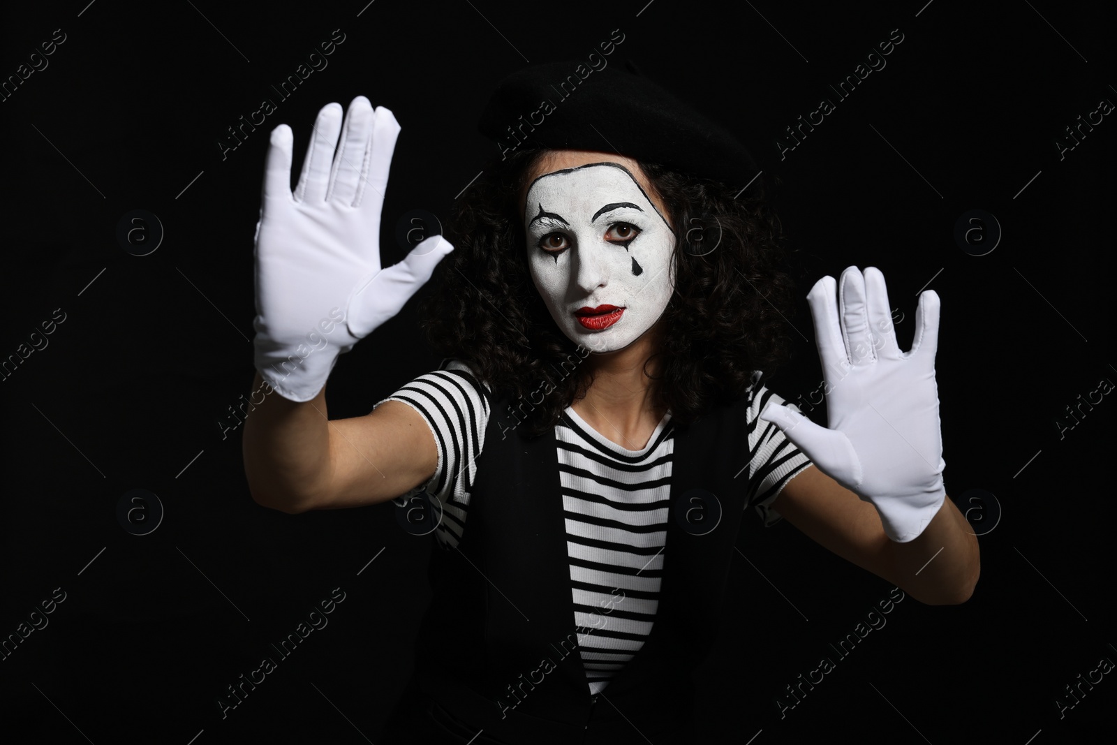 Photo of Young woman in mime costume posing on black background