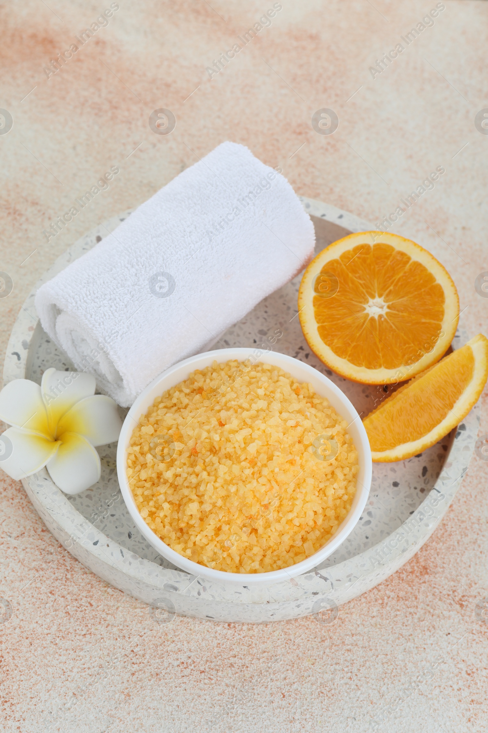 Photo of Sea salt, towel, plumeria flower and cut orange on beige textured table, above view