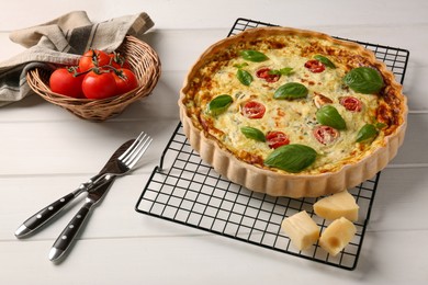 Photo of Delicious homemade cheese quiche, ingredients and cutlery on white wooden table