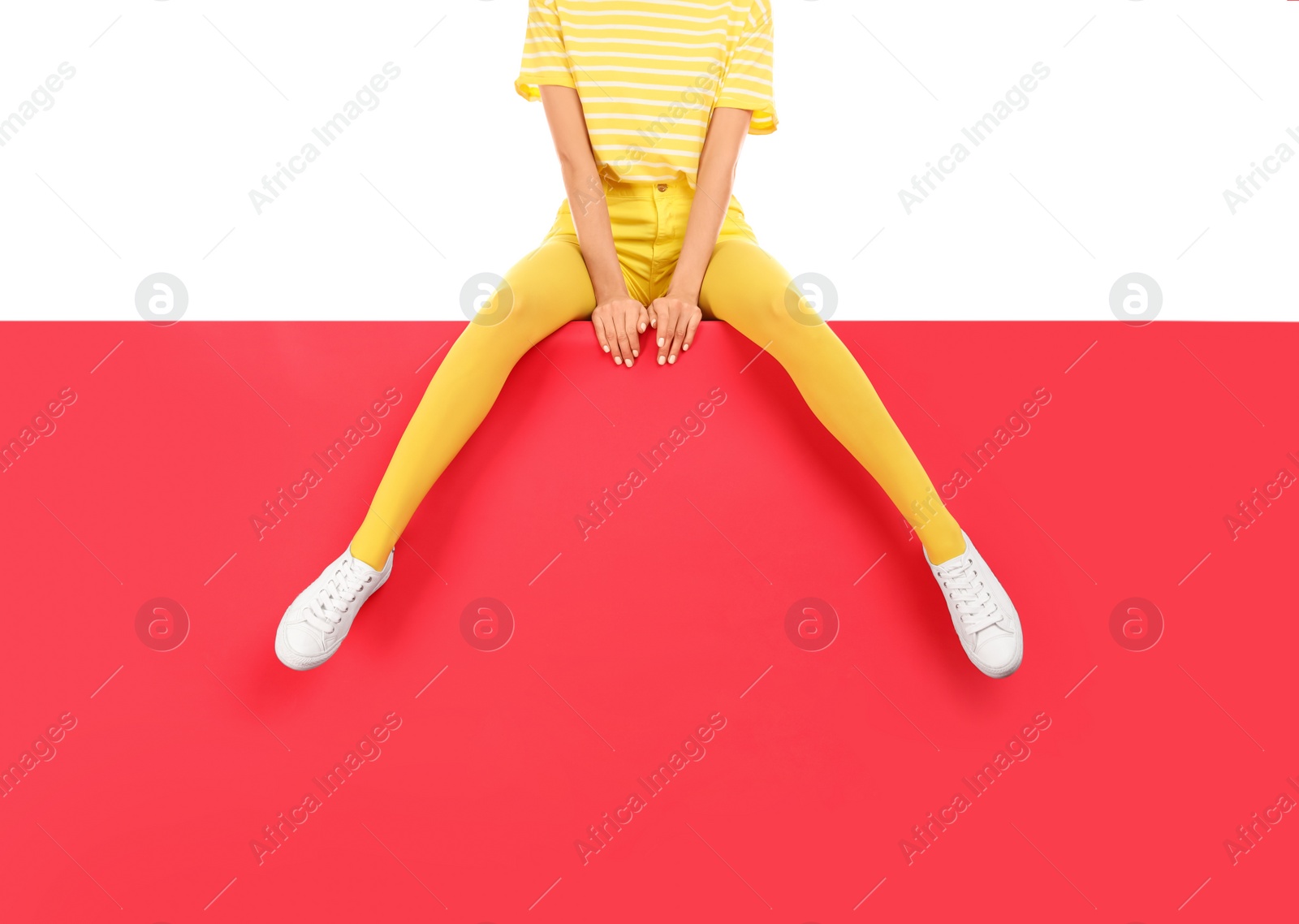 Photo of Woman wearing yellow tights sitting on color background, closeup