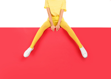 Photo of Woman wearing yellow tights sitting on color background, closeup