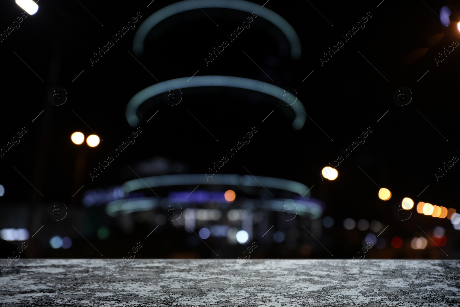 Image of Empty stone surface and blurred view of night city