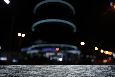 Image of Empty stone surface and blurred view of night city