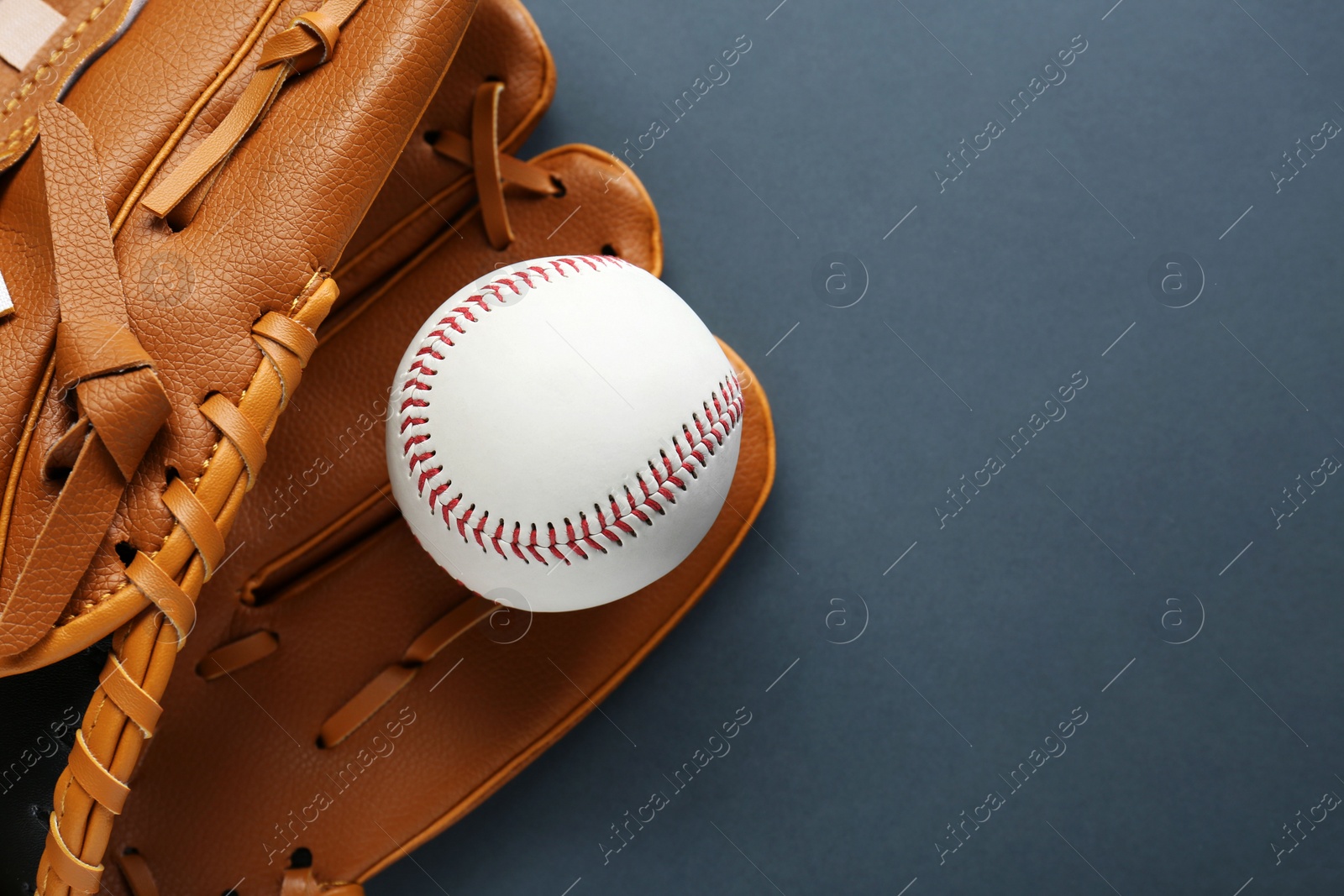 Photo of Catcher's mitt and baseball ball on dark background, top view with space for text. Sports game