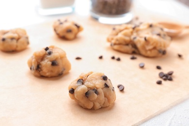 Photo of Cookie dough with chocolate chips on parchment, closeup