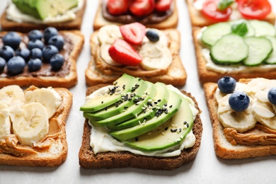 Photo of Tasty toast bread with fruits, berries and vegetables on light background, closeup