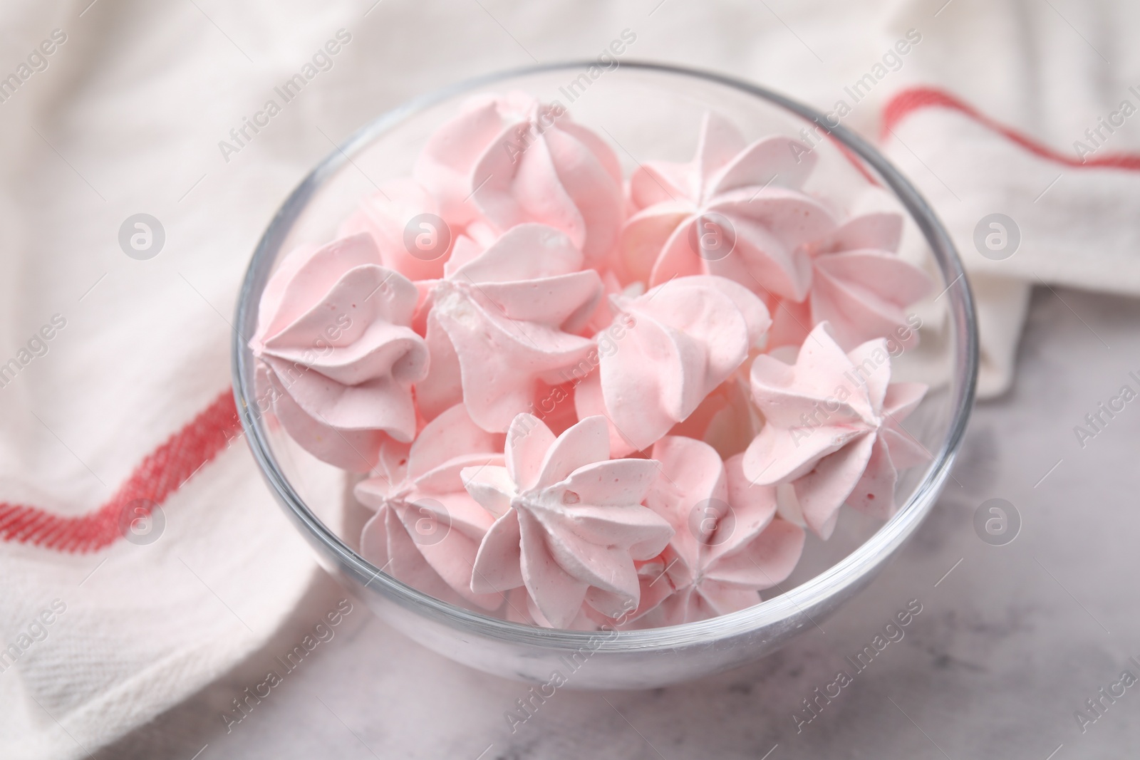 Photo of Tasty meringue cookies in bowl on white marble table