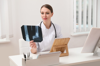 Orthopedist examining X-ray picture at desk in clinic