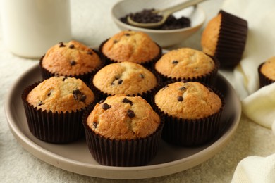 Photo of Delicious sweet muffins with chocolate chips on light textured table, closeup