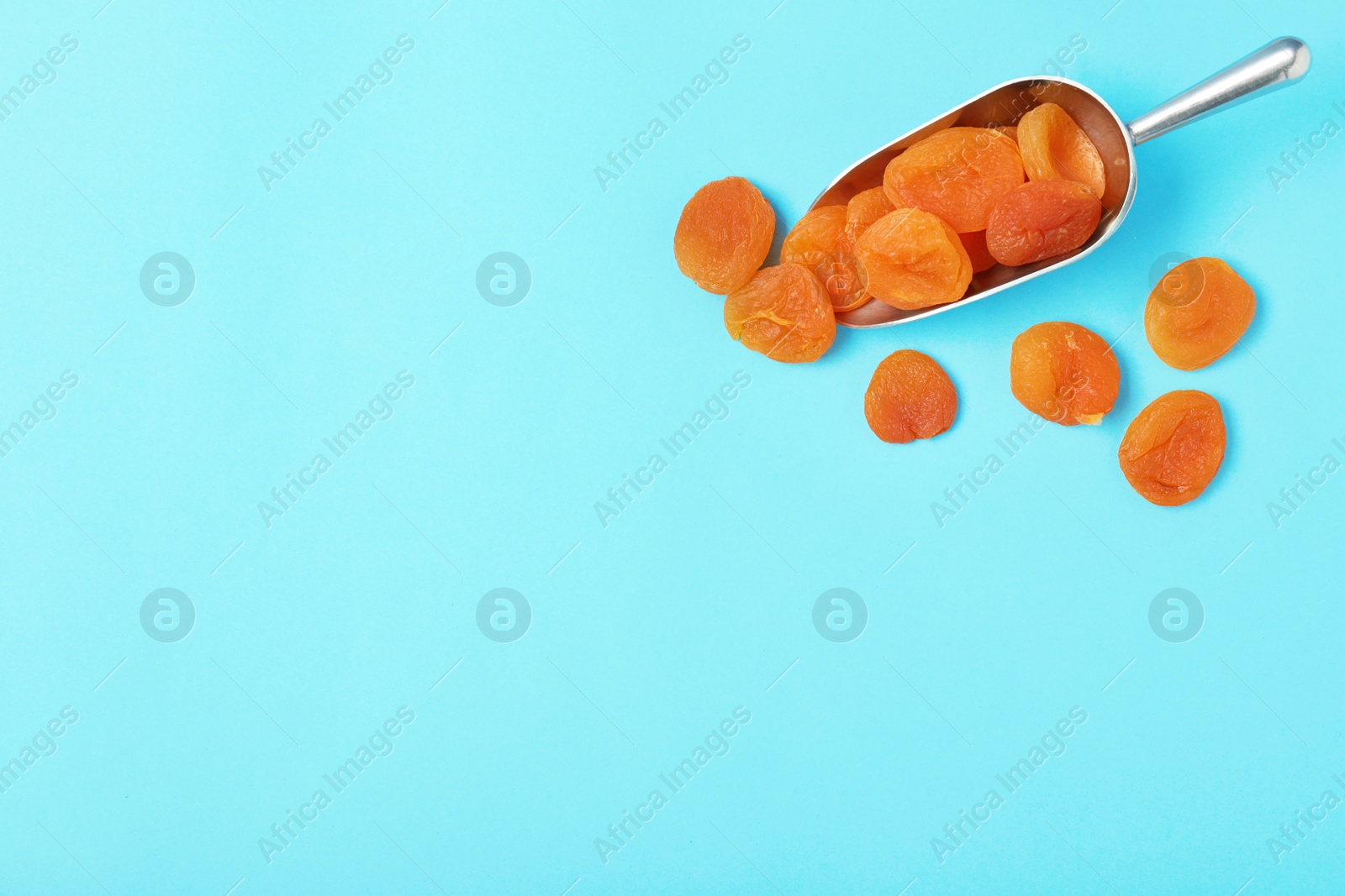 Photo of Scoop of dried apricots on color background, top view with space for text. Healthy fruit