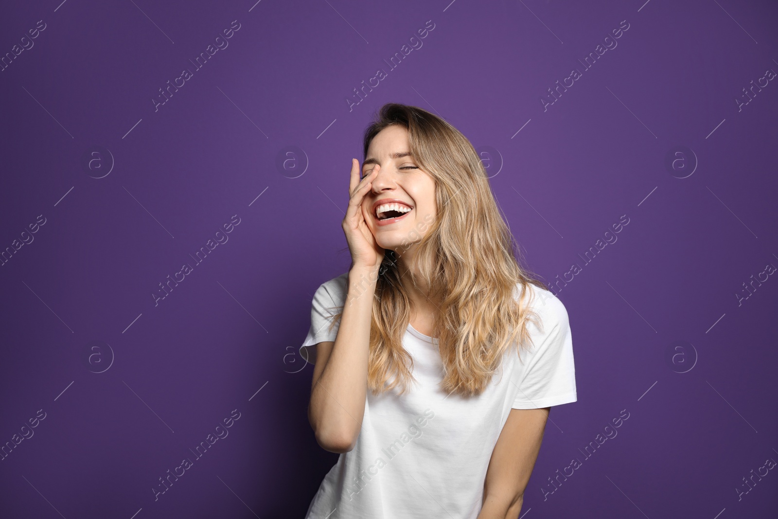 Photo of Cheerful young woman laughing on violet background