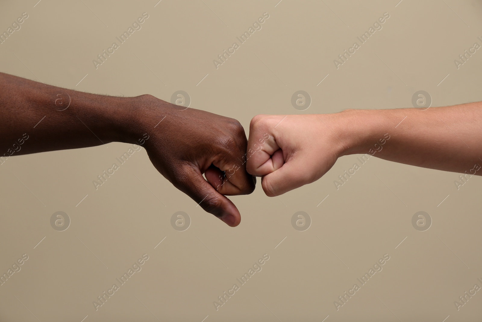 Photo of Men making fist bump on beige background, closeup