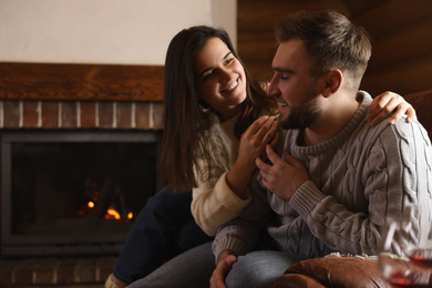 Photo of Lovely couple resting near fireplace at home. Winter vacation