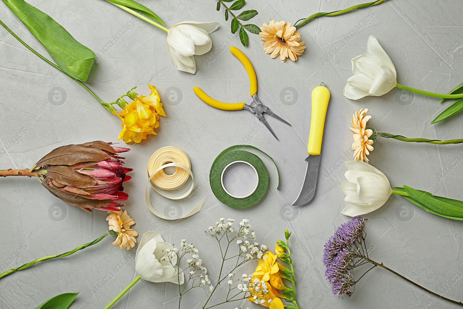 Photo of Florist equipment with flowers on gray background, top view