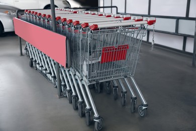 Photo of Row of empty metal shopping carts near supermarket outdoors