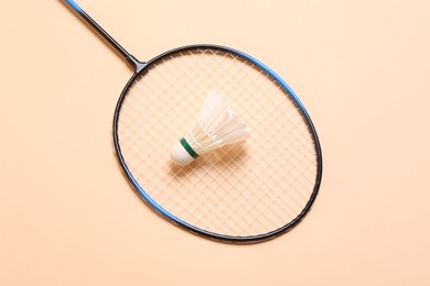 Photo of Feather badminton shuttlecock and racket on beige background, top view