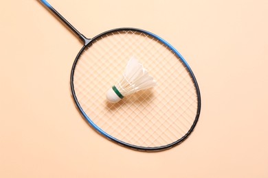 Feather badminton shuttlecock and racket on beige background, top view