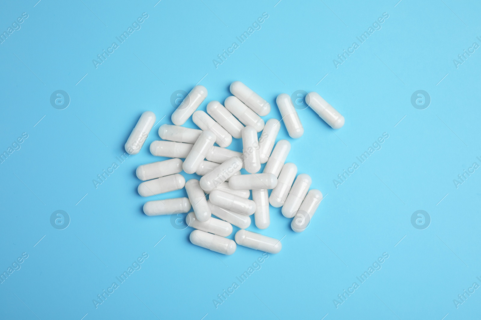 Photo of Pile of amino acid pills on light blue background, flat lay