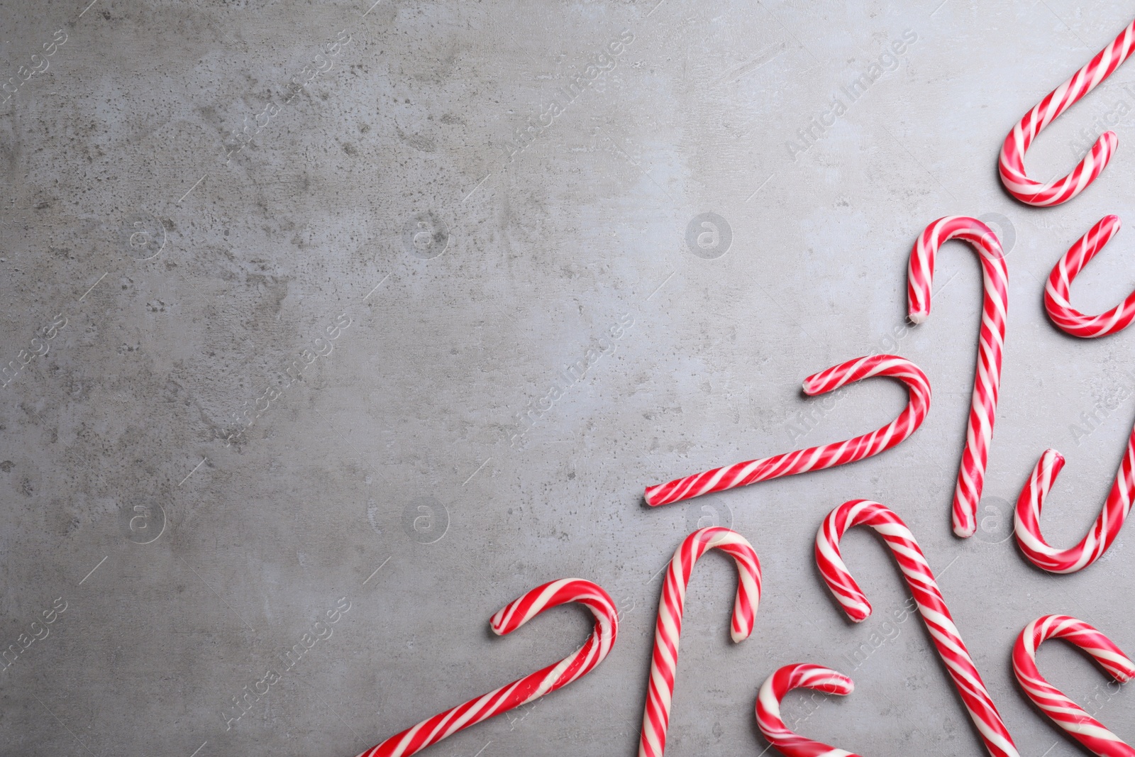 Photo of Sweet Christmas candy canes on grey background, flat lay. Space for text