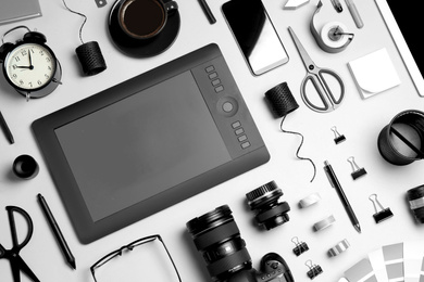 Photo of Flat lay composition with graphic drawing tablet and different office items on light background. Designer's workplace