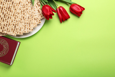 Matzos, Torah and flowers on green background, flat lay with space for text. Passover (Pesach) Seder