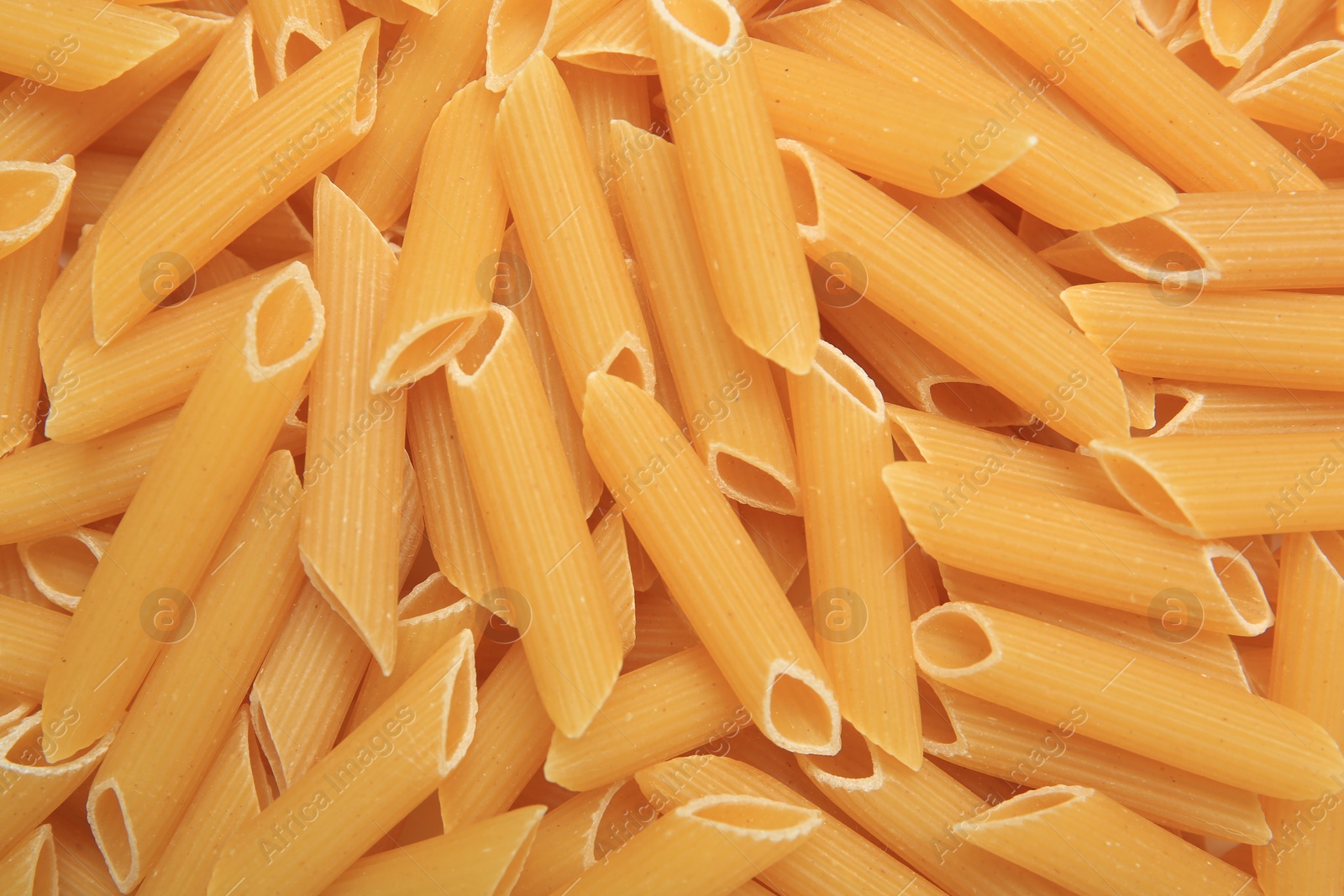 Photo of Uncooked penne pasta as background, top view