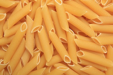 Uncooked penne pasta as background, top view