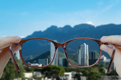 Image of Vision correction. Woman looking through glasses and seeing landscape clearer