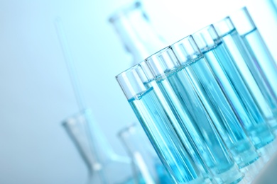 Photo of Test tubes with liquid on blurred background, closeup with space for text. Solution chemistry