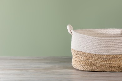 Empty wicker laundry basket near light green wall. Space for text