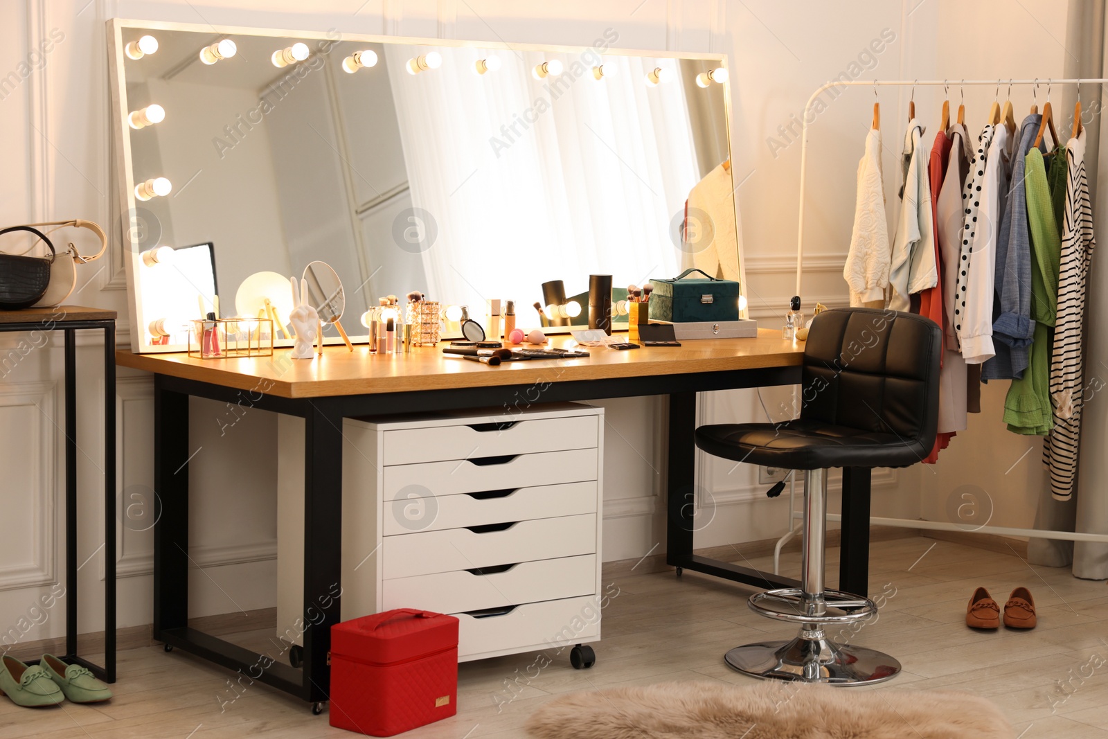 Photo of Makeup room. Stylish dressing table with mirror, chair and clothes rack