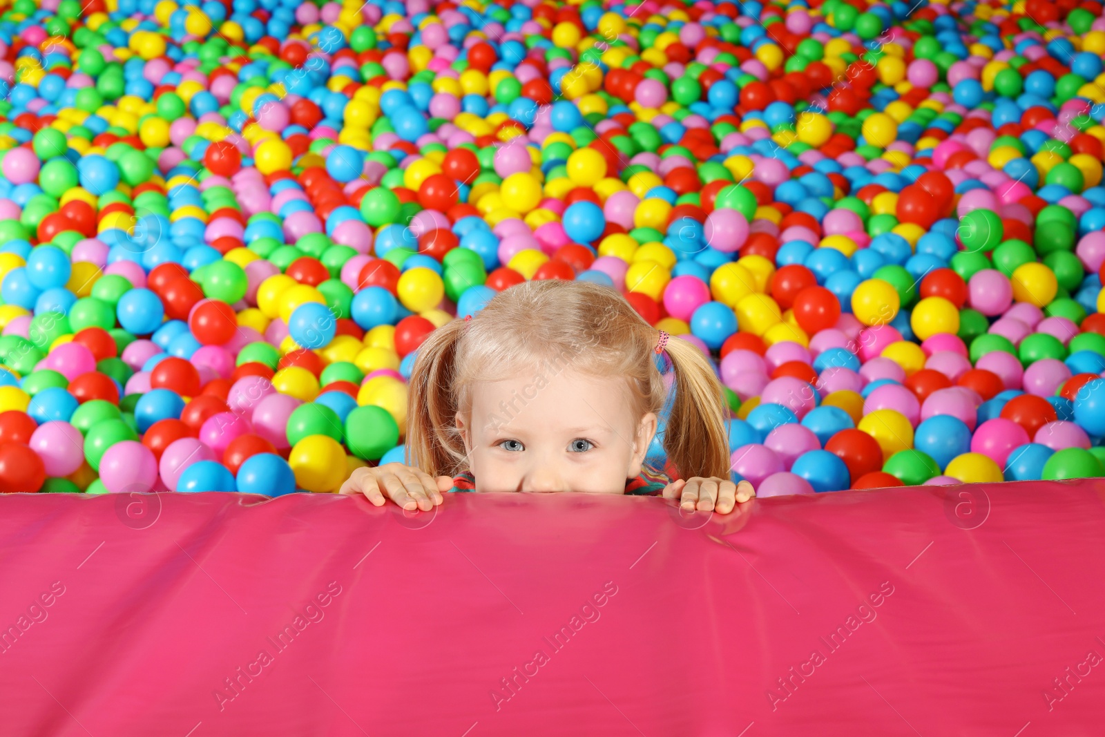 Photo of Cute child playing in ball pit indoors