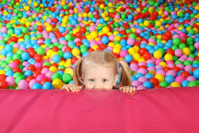Cute child playing in ball pit indoors