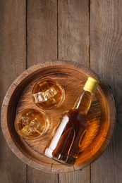 Whiskey with ice cubes in glasses, bottle and barrel on wooden table, top view