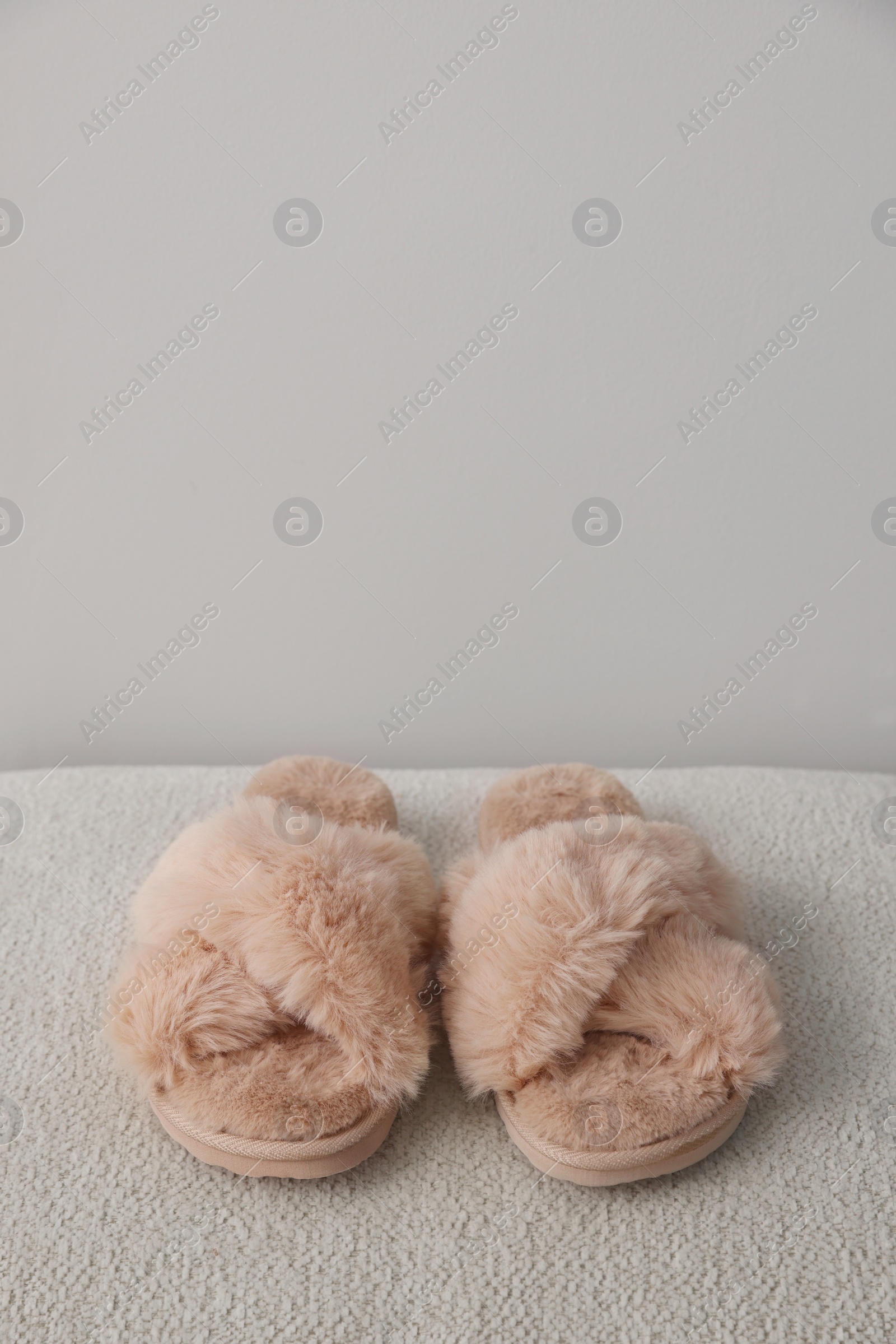 Photo of Soft beige slippers near grey wall, space for text