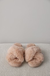 Soft beige slippers near grey wall, space for text
