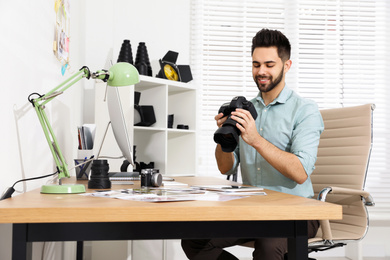 Photo of Professional photographer with camera working at table in office