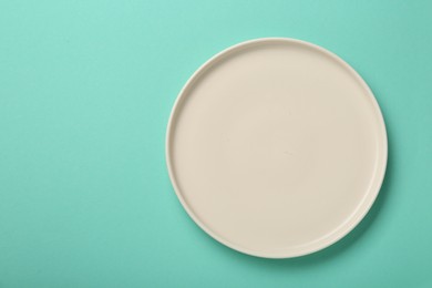 Empty ceramic plate on turquoise background, top view. Space for text